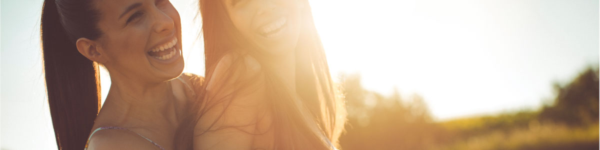 Two youthful women smilling with lens flare from sun's light