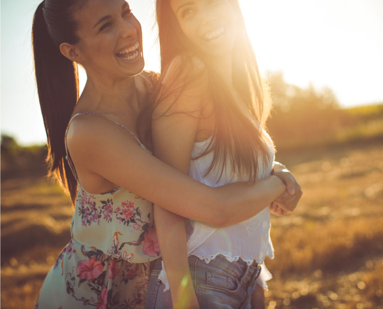 Two youthful women smilling with lens flare from sun's light
